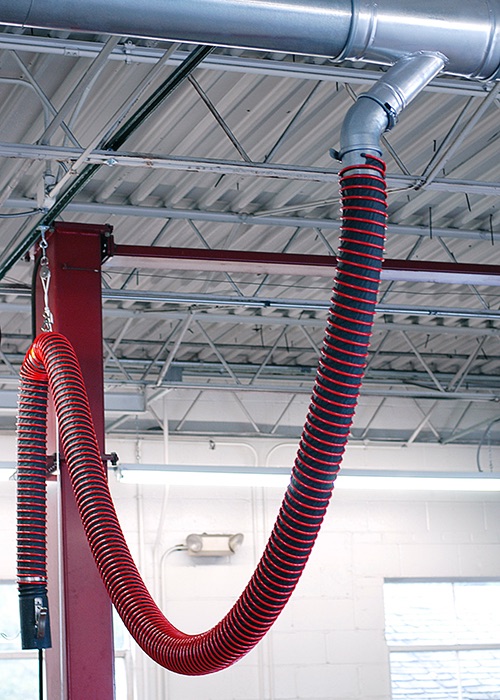 Fume-A-Vent vehicle exhaust removal system shown installed in a repair garage to extract fumes and other air contaminants.