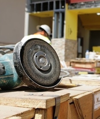 Close-up of a sander while machine operators work on projects in the background.